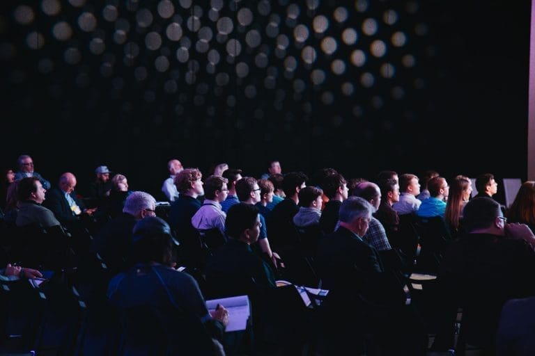 Audience seated in a darkened room watching a presentation